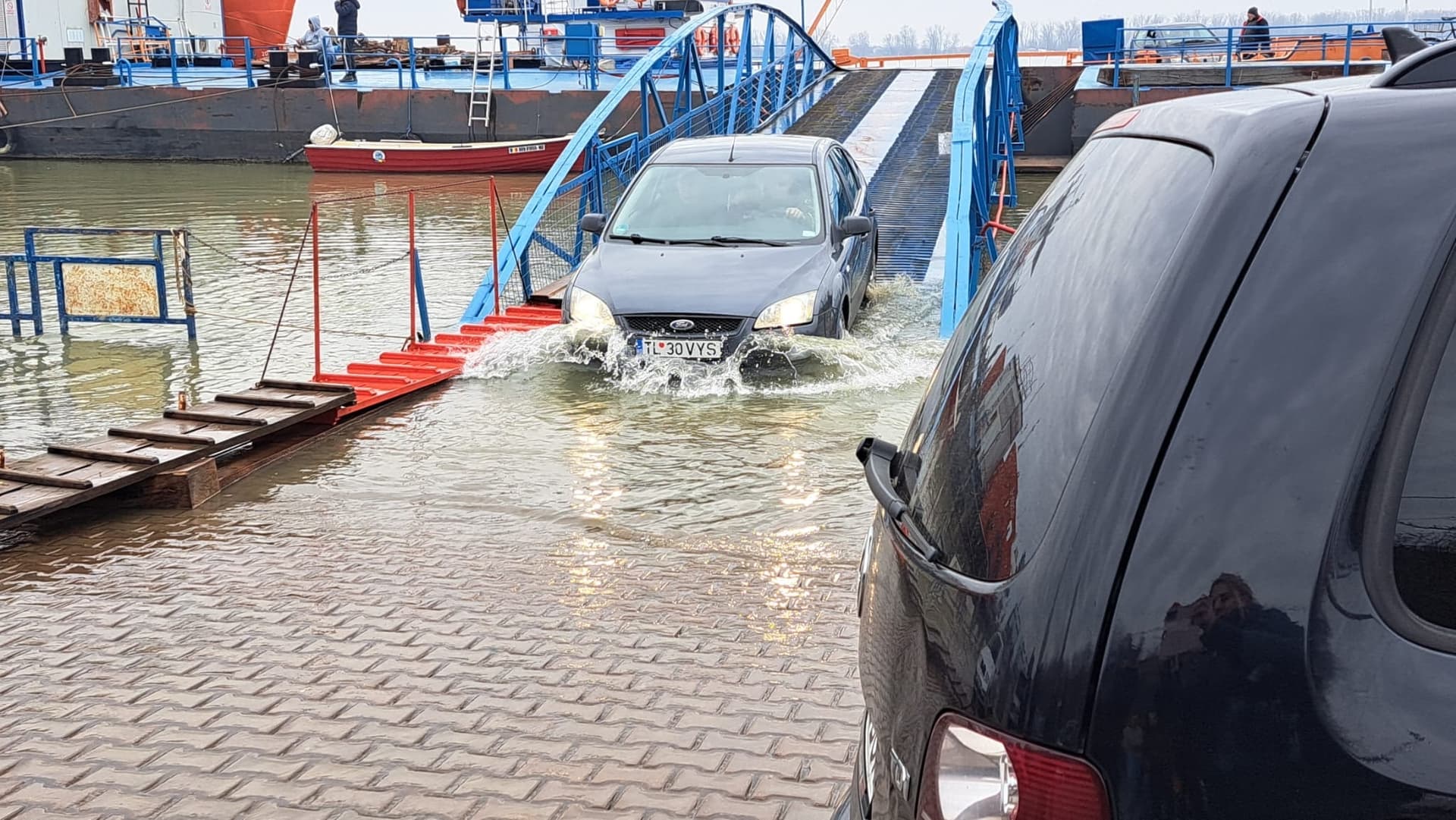 Maşinile trec prin apă ca să poată urca pe bacul de la Galaţi / Dunărea are debitul mult mai mare decât de obicei