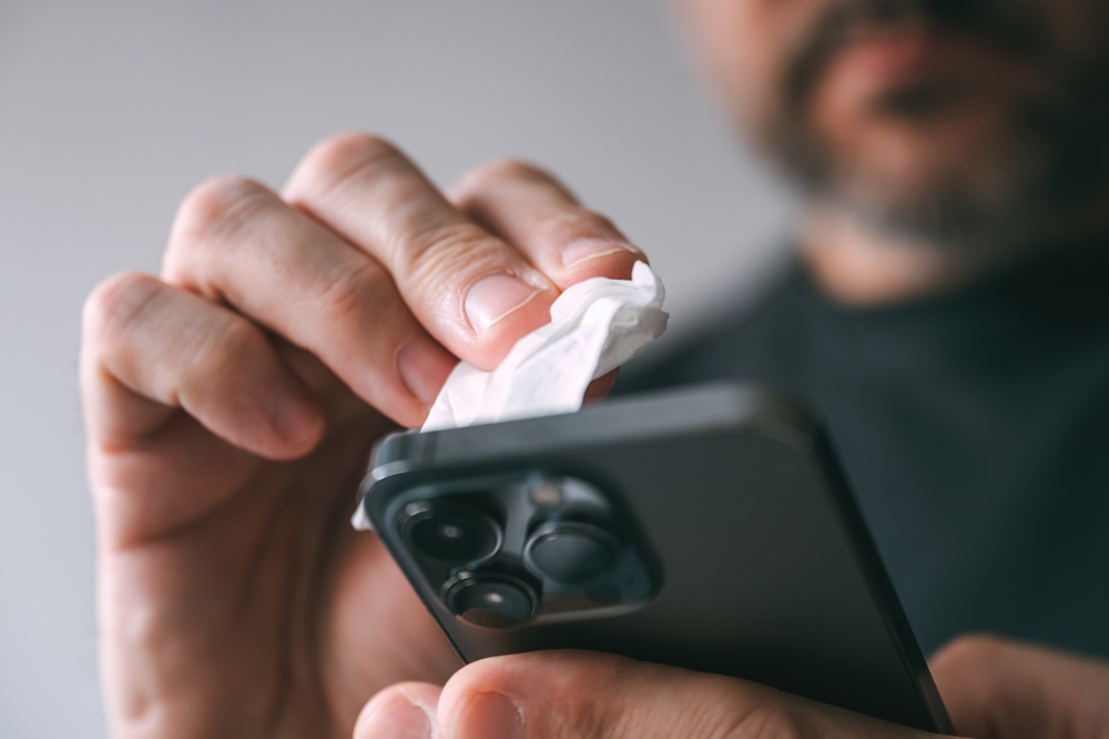 O persoană curățând ecranul unui telefon mobil